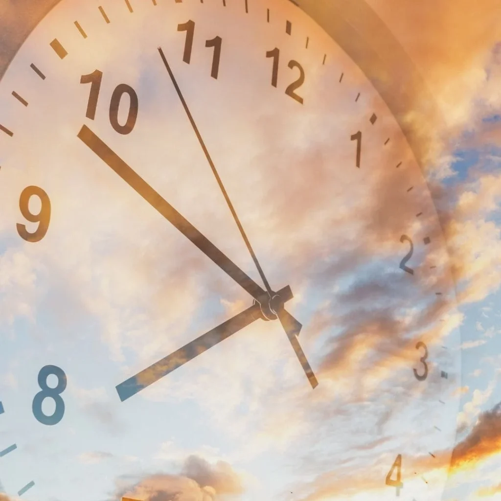 Quadrante di un orologio sovrapposto a un cielo al tramonto: la gestione del tempo